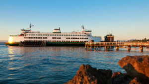 A white-and-green Washington State ferry docked at Bainbridge Island at sunset.