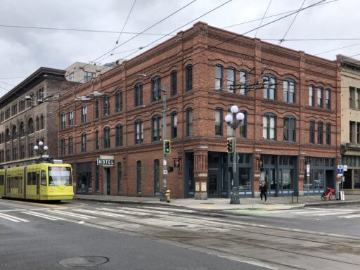 A three-story brick building with a yellow streetcar passing by outside.