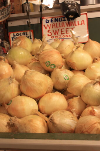 A pile of Walla Walla sweet onions, golden yellow and about the size of baseballs.