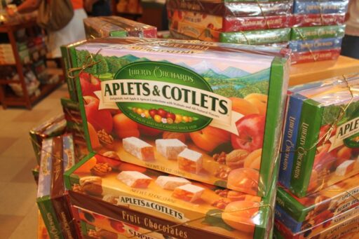 A stack of boxes of Liberty Orchards Aplets and Cotlets, with art showing cubes of sugar-coated fruit jelly in front of apples, apricots, and nuts, with a mountainous landscape in the background.