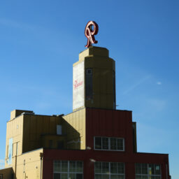 The old Rainier brewery, a large, blocky, industrial building, with a large, ornate, rotating red R sign on top.