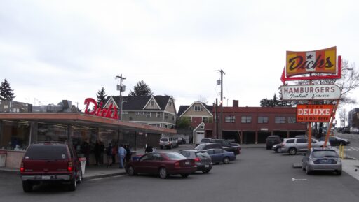 The Wallingford Dick's Drive In, a walk-up hamburger stand surrounded by cars, with lines of people at the order windows.