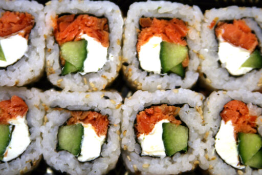 Eight Seattle roll sushi seen end-on, showing the white rice outer ring and orange, white, and green innards.