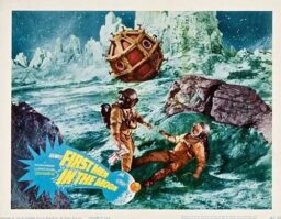 Lobby card for First Men in the Moon, featuring two astronauts on the moon, one reaching out to help the other who is lying on the ground, in front of a steampunk-looking dodecahedron space ship.