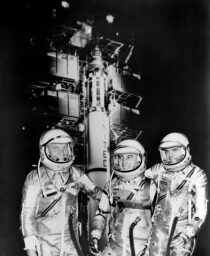 Mercury astronauts John H. Glenn Jr., Virgil I. Grissom and Alan B. Shepard Jr. standing by the Redstone rocket in their spacesuits.