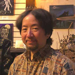 A smiling mixed-race man in a patterned shirt smiles at the camera.