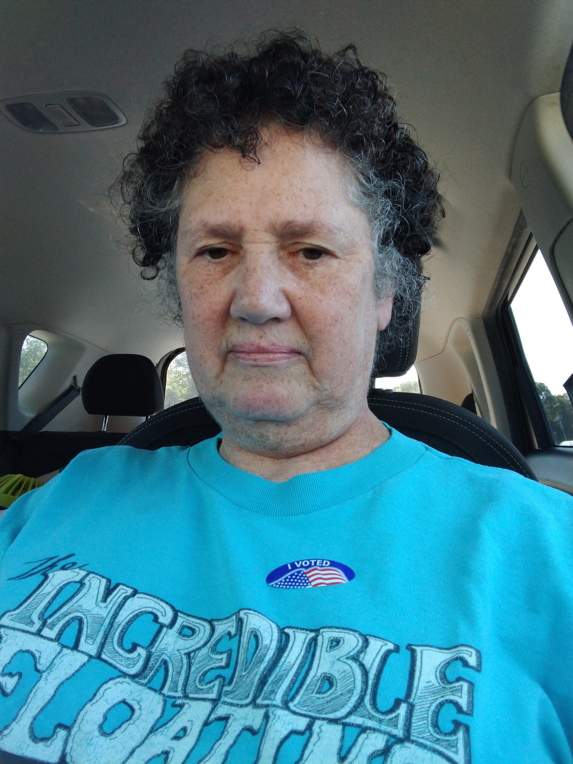 A grumpy, frumpy looking artist wearing a teal Incredible Floating Easter Coast Art Show Crew t-shirt