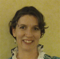 A photo of the artist, she has her hair twisted back on the sides and has a pleasant smile.