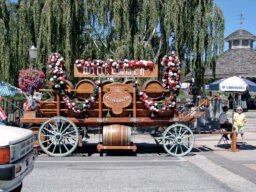 A large wooden cart with beer barrels, decked in red and white flower garlands, with a sign that says wilkommen in Leavenworth.