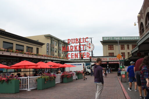 The main entrance to the Pike Place Market, a cobblestone lined street leading to the famous red neon Public Market Center sign and clock.