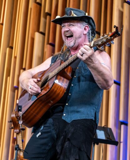 Guest of Honor Alexander James Adams playing guitar and singing for an audience.
